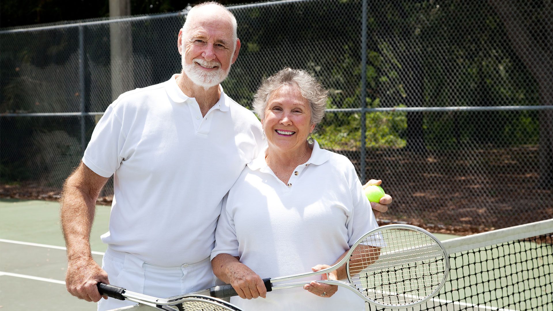 Male and Female senior tennis players next to net